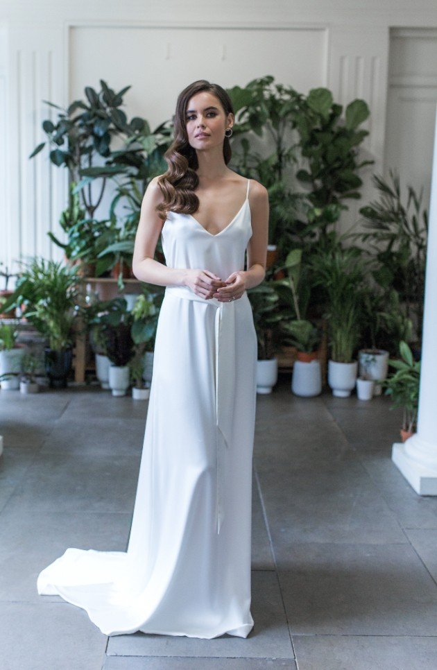 Bride wearing simple ivory wedding dress with spaghetti straps.