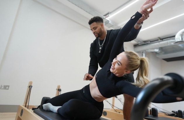woman on a bench doing a stretch, helped by an instructor