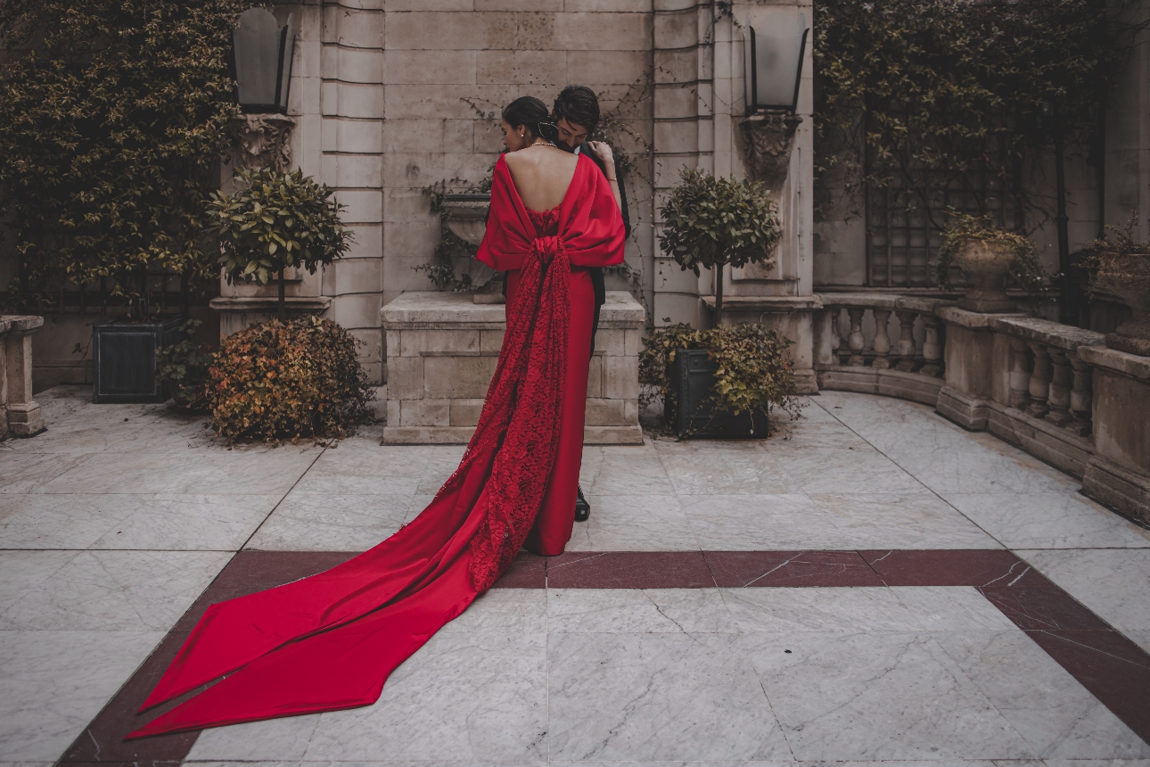 man in tux model in red dress embracing