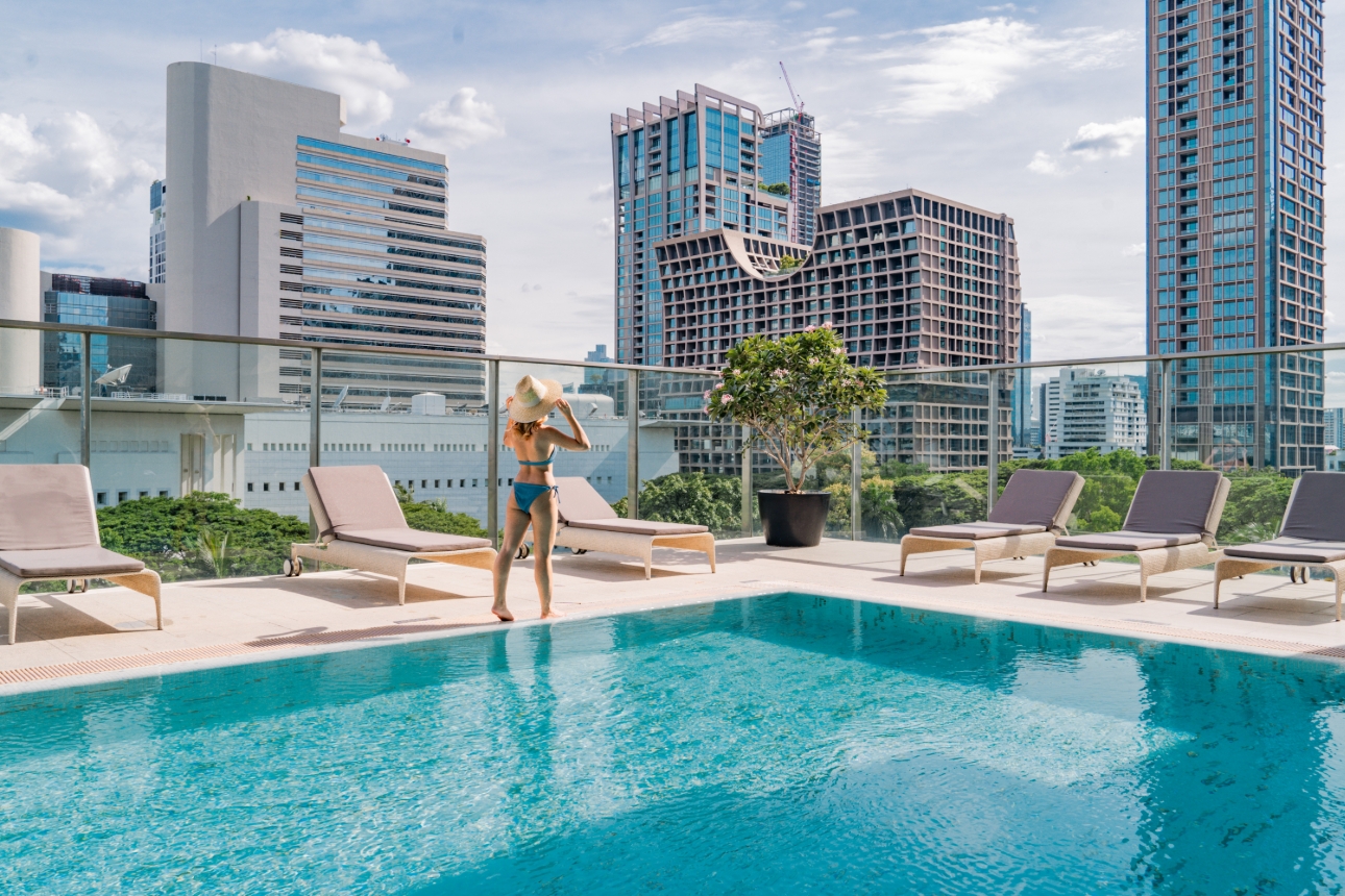 woman walking side of pool with city scape